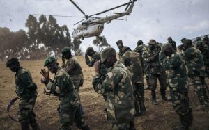 Des soldats de l'armée congolaise se protègent le visage au moment de l'atterissage d'un hélicoptère de la Monusco à Bijombo, en RDC, le 10 octobre 2020 afp.com - ALEXIS HUGUET