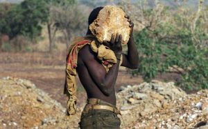 Un chercheur d'or transporte une pierre pour la concasser et y trouver des traces d'or ,le 14 mars 2002 près du village de Bagassi, au Burkina Faso afp.com - GEORGES GOBET