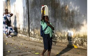 Un jeune homme porte un jerricane d'eau sur sa tête à Douala, le 10 janvier 2022 afp.com - Charly TRIBALLEAU